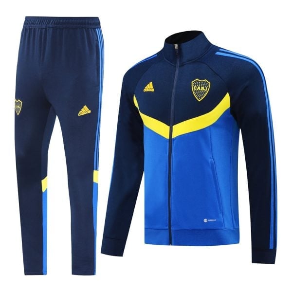 Blue and royal blue tracksuit set: zipper jacket with yellow chevron and club crest, matching pants with Adidas stripe details along the sides.