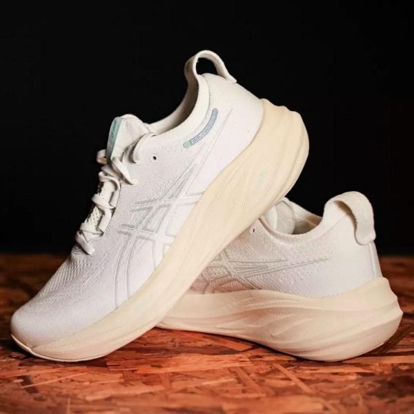 Pair of white running shoes with pale beige soles on a wooden surface against a dark background, shown in a side-by-side pose.