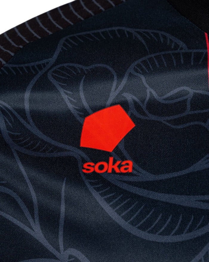 9KGJqM5CaUFtaV0 | AE JERSEY Close-up of dark navy fabric featuring a red geometric logo and the word 'soka' beneath it.