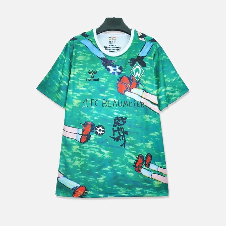 9db620f4cbfb46bdb11588eed606eb27_720x_4e4aab5f-a54b-4195-9cfa-807736d2bca7 | AE JERSEY Green graphic soccer jersey on a hanger with playful arm illustrations, featuring the 1. FC Blaumeier name and the hummel logo.