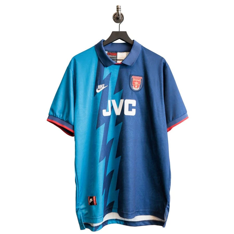 Arsena_blue_light_blue_jersey_nike_2XL_front | AE JERSEY Blue and teal soccer jersey with JVC sponsor, Nike logo, and team crest, hanging on a hanger against a white background.