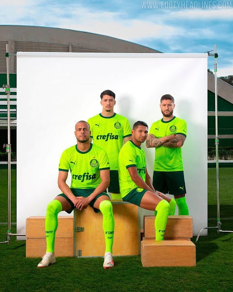 BrazilianclubPalmeirashavelaunchedtheirthirdshirtforthe2023-2024season.TheshirtisofficiallynamedTheHeartoftheThirdAcademyandissaidtosymbolizethepassiona_4_775655c7-6dd0-4c47-9973-c89035a1c1ad | AE JERSEY Four soccer players in neon green jerseys pose for a team photo in front of a white backdrop outdoors, with sponsor 'crefisa' visible on their shirts.
