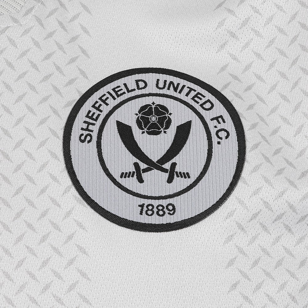 CoRws3ktgNz1QDD_4f92f828-7945-4158-ac5d-77b10cd575d0 | AE JERSEY Circular Sheffield United Football Club logo on a textured background, featuring crossed swords and a rose with 1889 text.