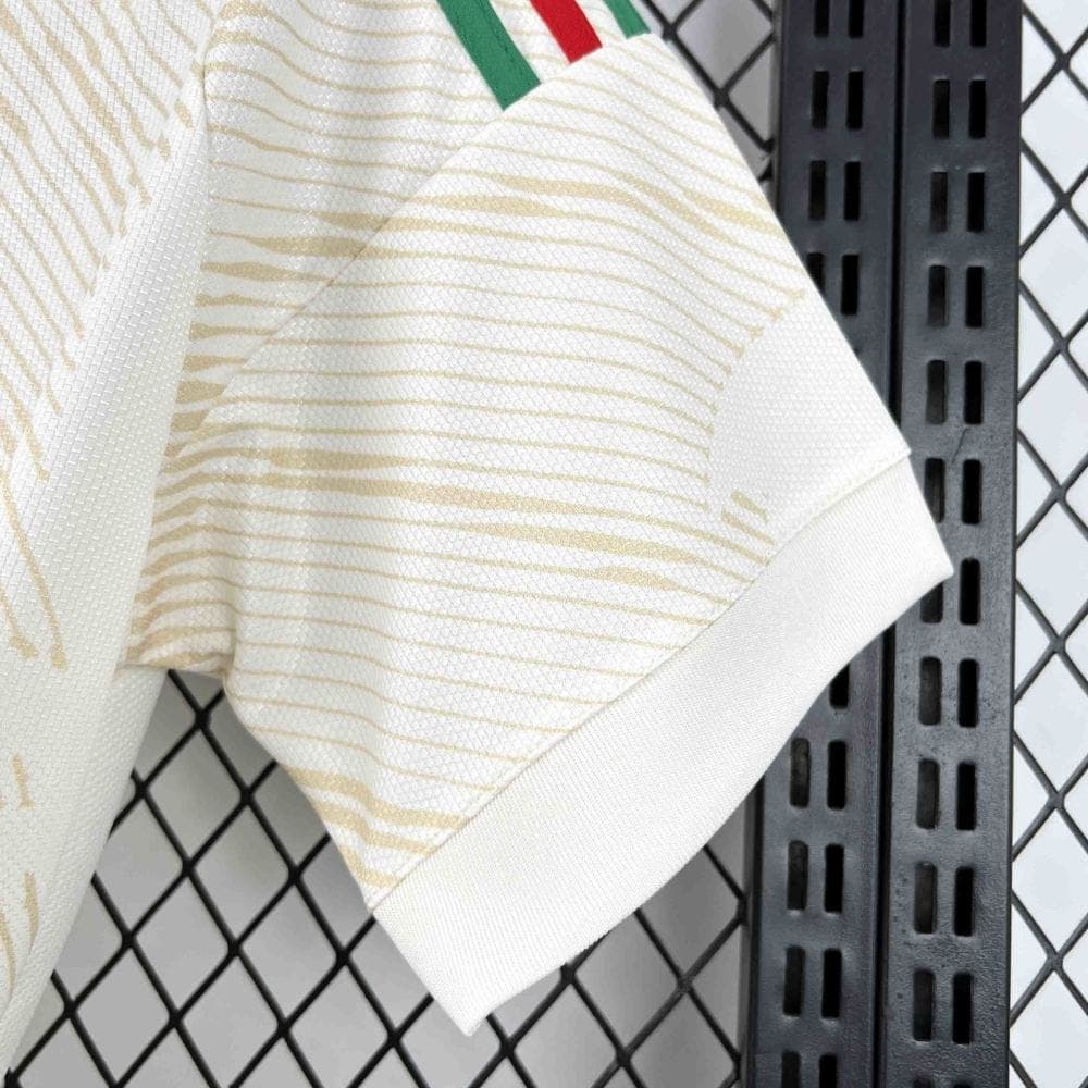 FB11E0B4-7D1B-4DC0-B13A-8F406D8555BF | AE JERSEY Close-up of a light beige striped polo sleeve draped over a black metal rack with a diamond-pattern chain-link fence in the background.
