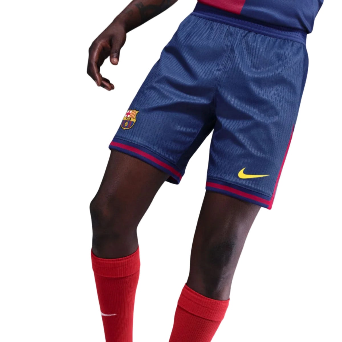 GW | AE JERSEY Partial view of a soccer player wearing blue Barcelona shorts with the club crest and a yellow Nike swoosh, and red socks.