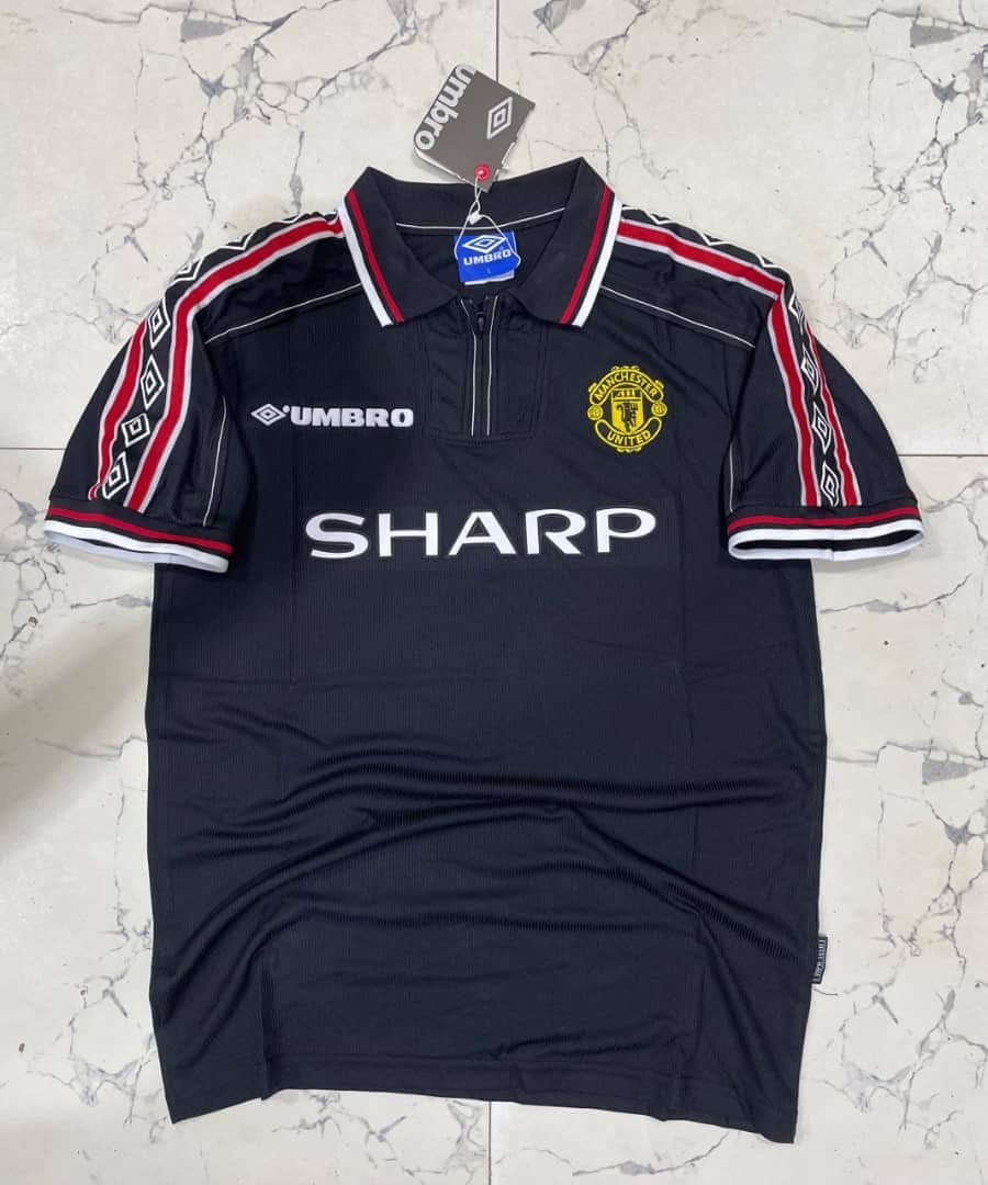 GYyp1g1XoAAvVc5 | AE JERSEY Dark Manchester United jersey on hanger featuring crest, Umbro logo, and 'SHARP' sponsor; navy with red-white trim.