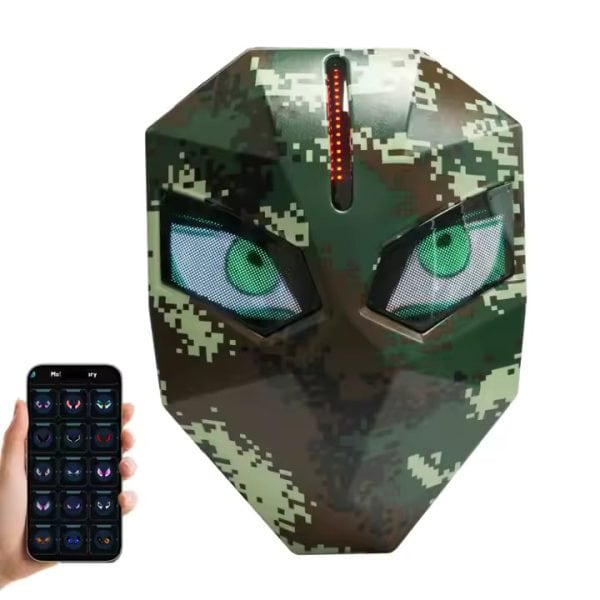 Camouflage digital mask with glowing green eyes and a vertical LED strip on the forehead, controlled by a smartphone app shown to the left.