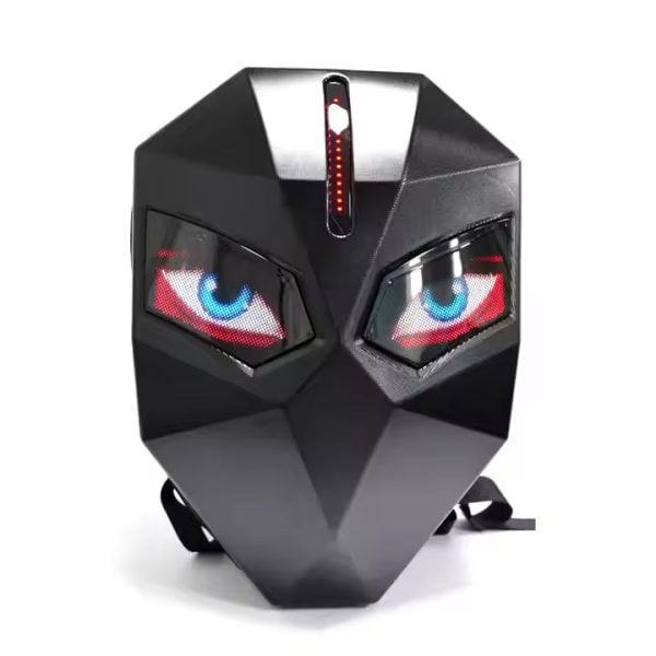 Black geometric mask with angular facets, glowing blue and red LED eyes, and a vertical LED strip on the forehead, placed on a white surface with straps visible underneath.