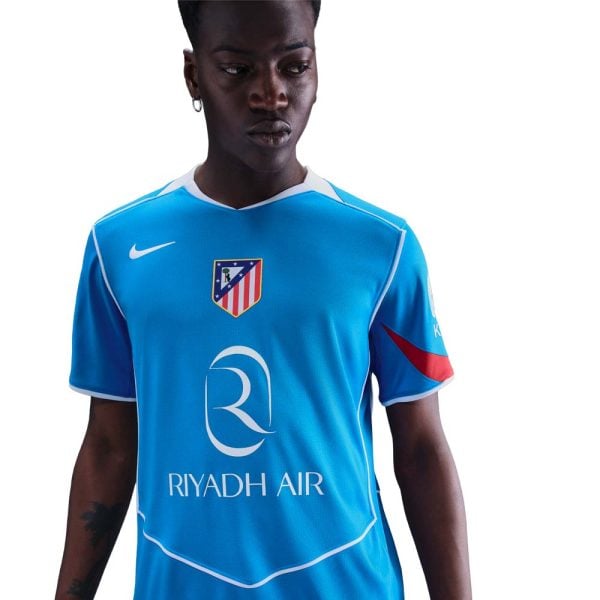 Person wearing a bright blue soccer jersey with Riyadh Air logo and an Atletico Madrid crest on the chest, white trim visible at collar and sleeves.
