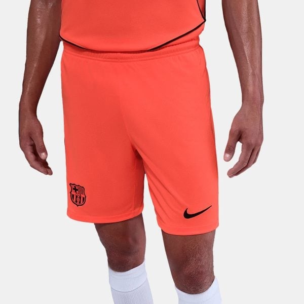 Male athlete wearing bright orange soccer shorts with FC Barcelona crest on the left leg and a black Nike swoosh, white socks visible.