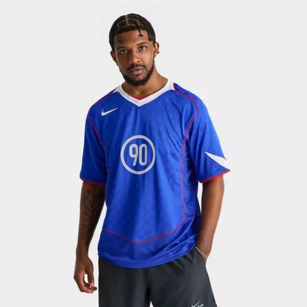 Man wearing a blue soccer jersey with a white circle and '90' on the chest, standing against a light background.