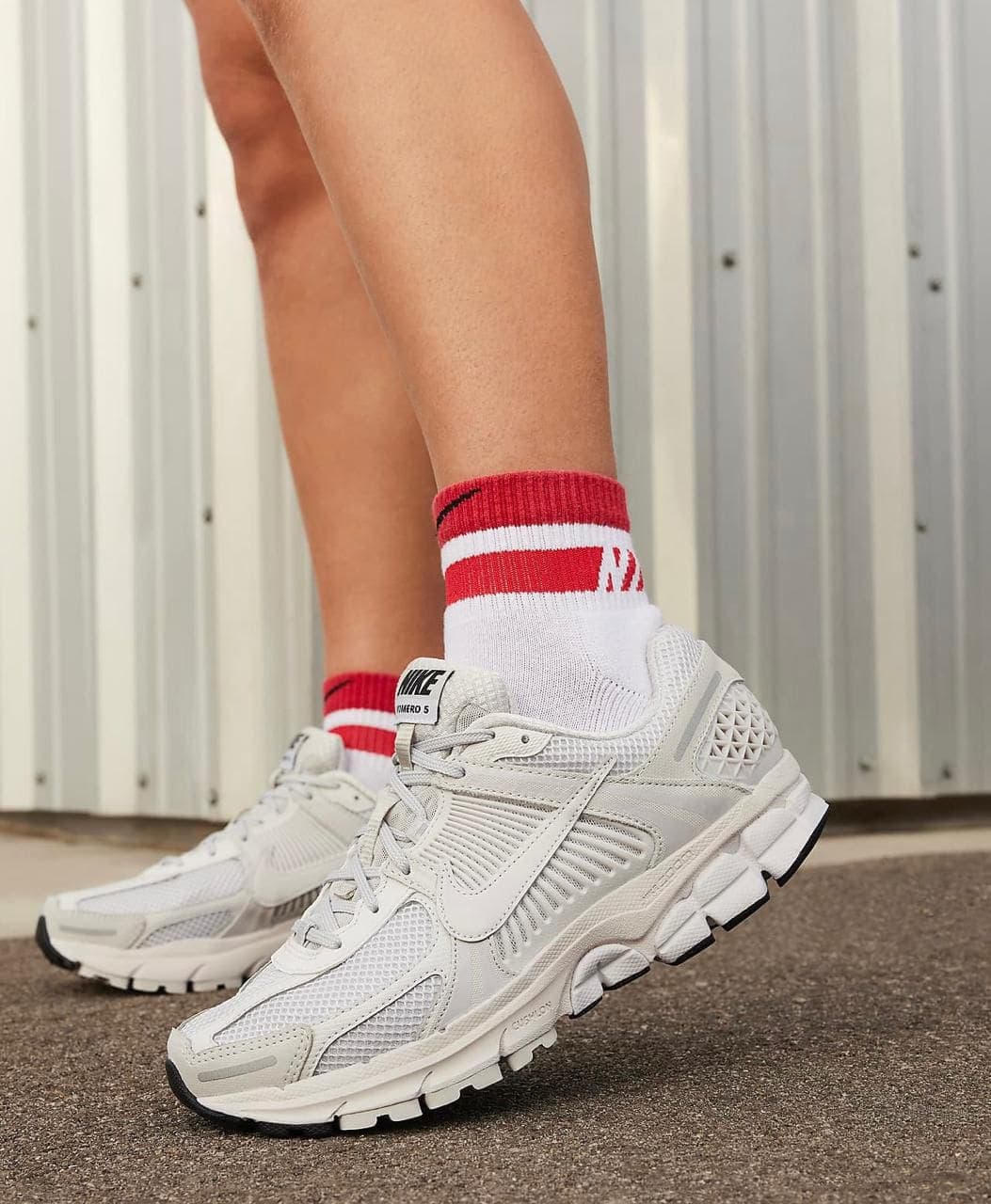 IMG-20240422-WA0012 | AE JERSEY Close-up of white sneakers and white socks with red stripes on a paved surface.