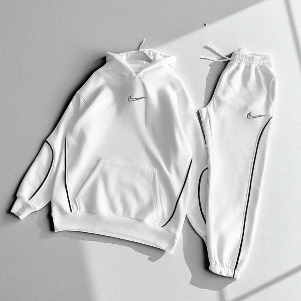 White Nike tracksuit: a hoodie with front pocket and drawstring hood paired with matching jogger pants featuring black piping accents.