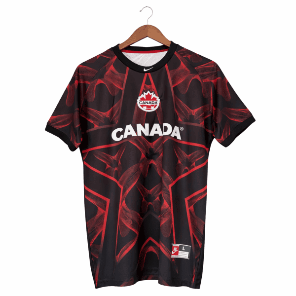 Black and red Canada soccer/athletic jersey on a wooden hanger, featuring the mapleleaf crest and bold 'CANADA' text across the chest