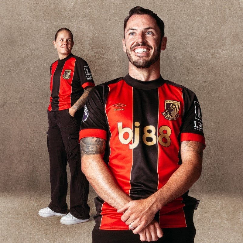 Jqj0xmu3cPDucnN | AE JERSEY Two men in red-and-black striped football jerseys pose against a plain wall; one stands in background, the other smiles broadly in front.
