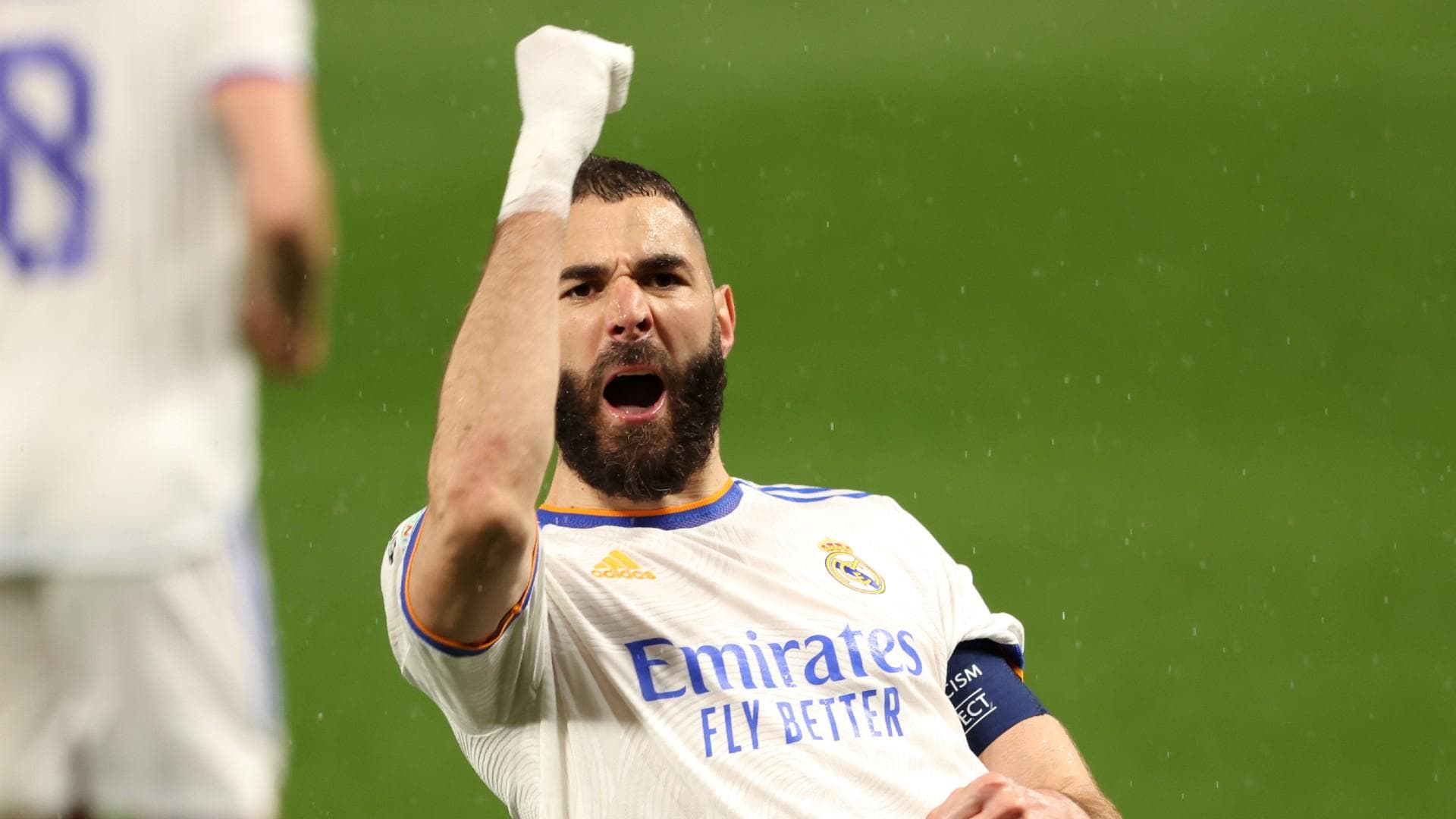 Karim_Benzema_Real_Madrid_vs._Chelsea_040622 | AE JERSEY Soccer player in a white Real Madrid kit celebrating with a raised fist in the rain.
