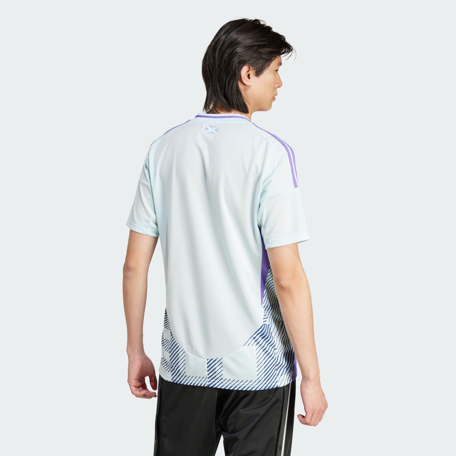 LP0NLV2Z7Jz0qKa | AE JERSEY Back view of a person wearing a light blue athletic jersey with purple stripes, standing against a pale background.