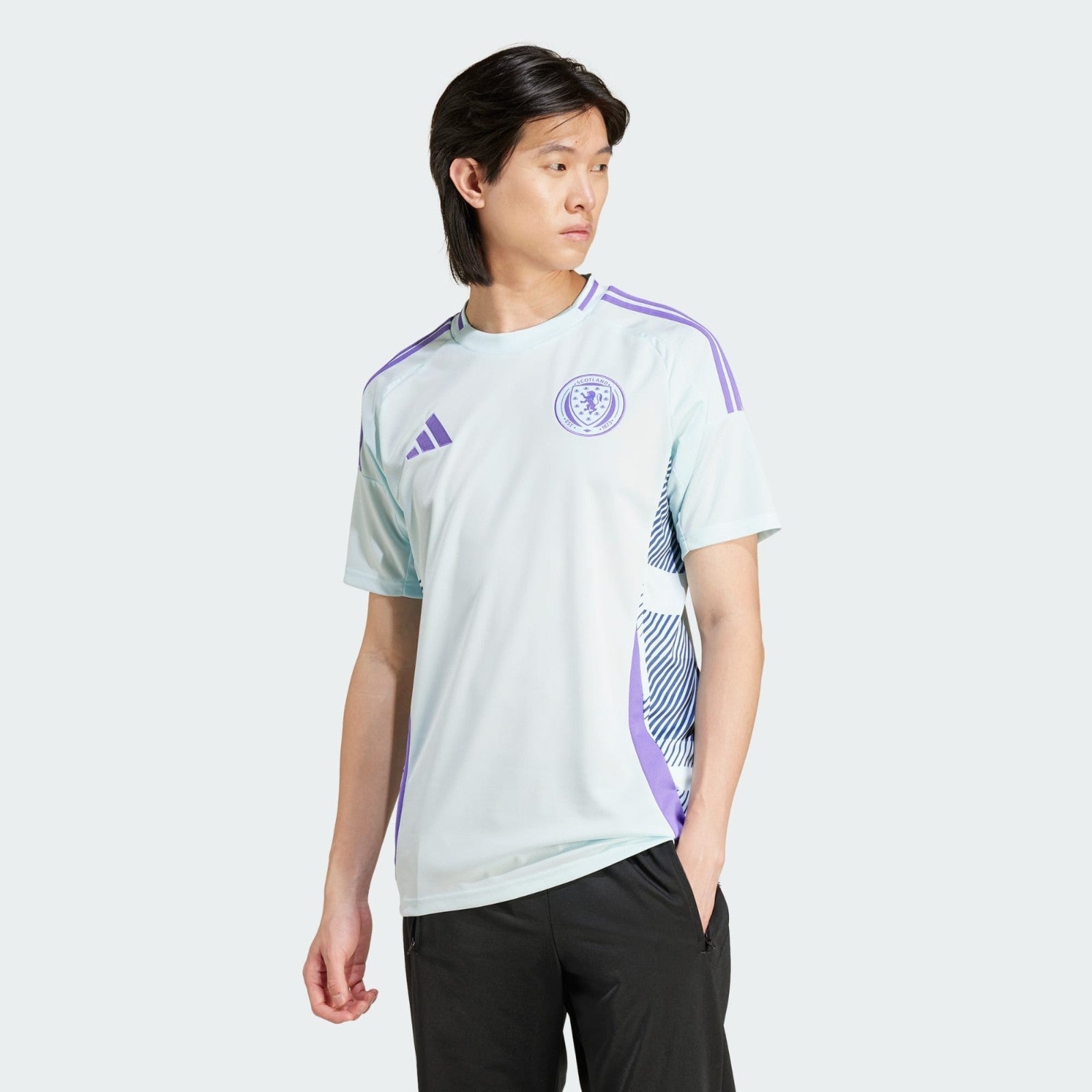 LXeCuSLtyjtCCWm | AE JERSEY Male model wearing a light blue Scotland jersey with purple stripes, facing left against a pale gray background, 3/4 view.