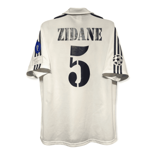 Back view of a white sports jersey with bold letters reading 'ZIDANE' and a large number 5 on the back, with patches on the sleeves.