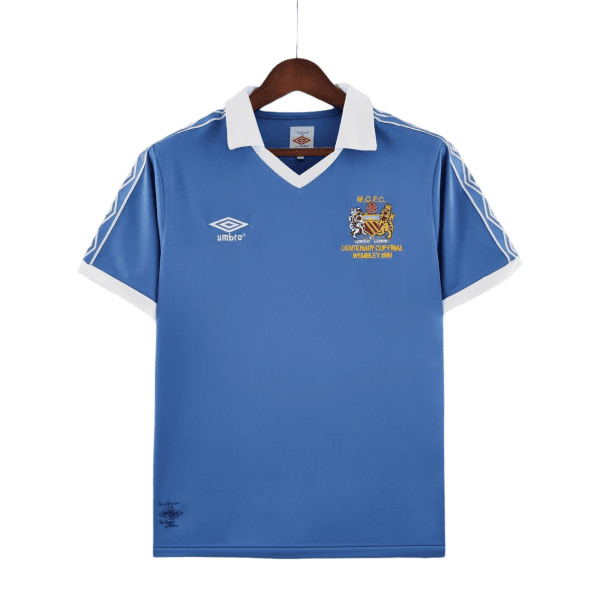 Blue football jersey on a wooden hanger with a white collar, featuring the Umbro logo on the left chest and a crest with Wembley 1981 text on the right.
