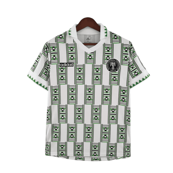 White football jersey on a hanger with green/black geometric patterns, Adidas logo, and Nigeria Football Federation crest.