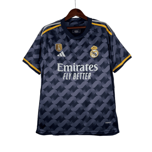 Real Madrid navy away jersey on hanger with Adidas logo and Emirates Fly Better slogan, yellow shoulder stripes, patterned design