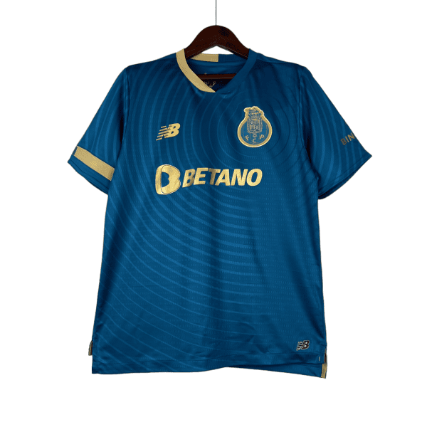Blue football jersey with gold trim on a hanger, featuring a club crest on the chest and New Balance logo, sponsorship by Betano.