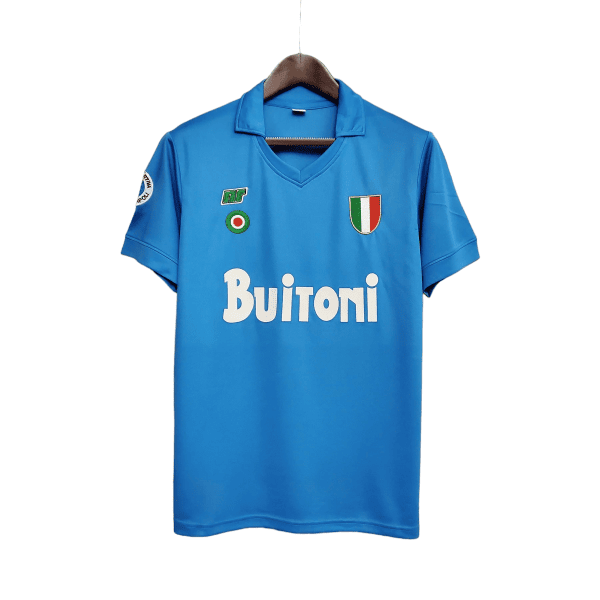 Blue sports jersey on a wooden hanger, features patch with Italian flag crest on the chest and sponsor text Buitoni across the front.