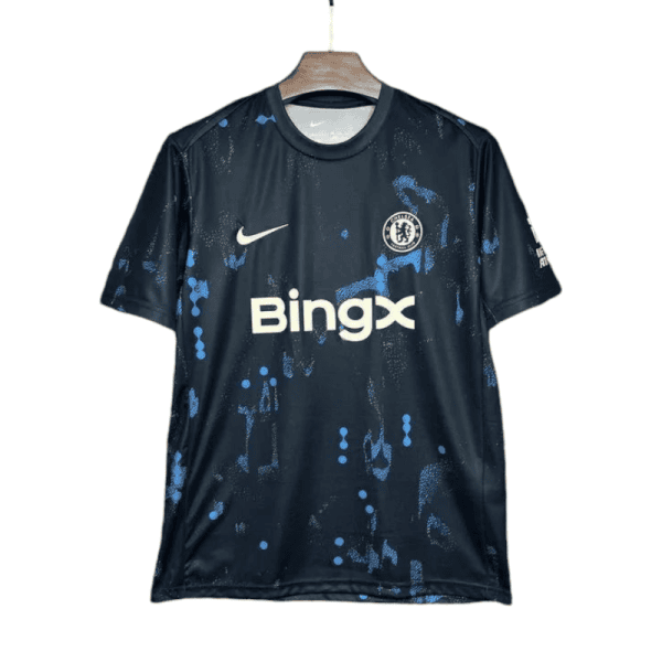 Dark blue Chelsea FC jersey with blue splatter pattern, Nike swoosh, sponsor BingX, hanging on a wooden hanger