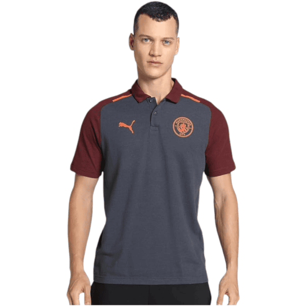 Male model wearing a navy polo shirt with maroon sleeves and collar, featuring an orange Puma logo and Manchester City crest on the chest.