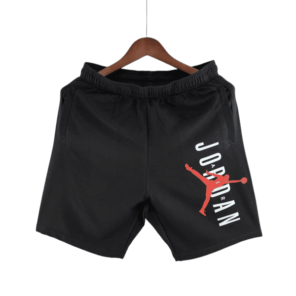 Black athletic shorts on a wooden hanger with a red Jumpman logo and white lettering along the side, hanging against a white background.
