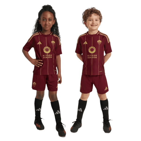 Two children in maroon Riyadh Season soccer kits stand side by side, smiling.