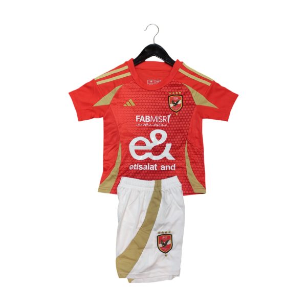 Red football jersey on a hanger with gold trim, crest, and sponsor text (Etisalat) visible on the chest area, paired with white shorts below.