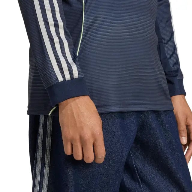 RMCFMZ0907_7 | AE JERSEY Close-up of a person wearing a navy athletic jacket with white stripes on the sleeve and dark jeans.