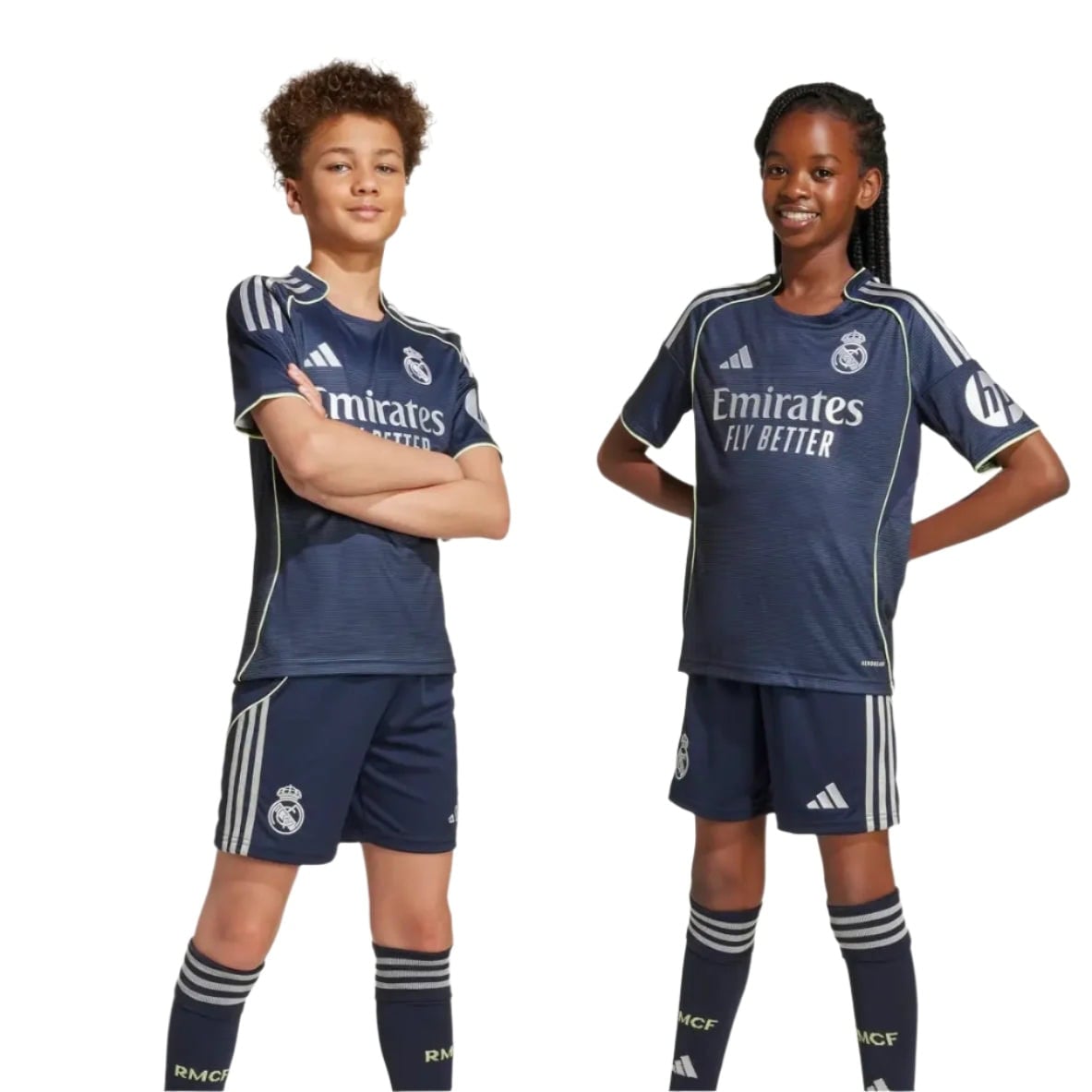 RMCFYO0095_12 | AE JERSEY Two young soccer players—a boy and a girl—in navy Real Madrid jerseys strike confident poses with hands on hips against a white background.