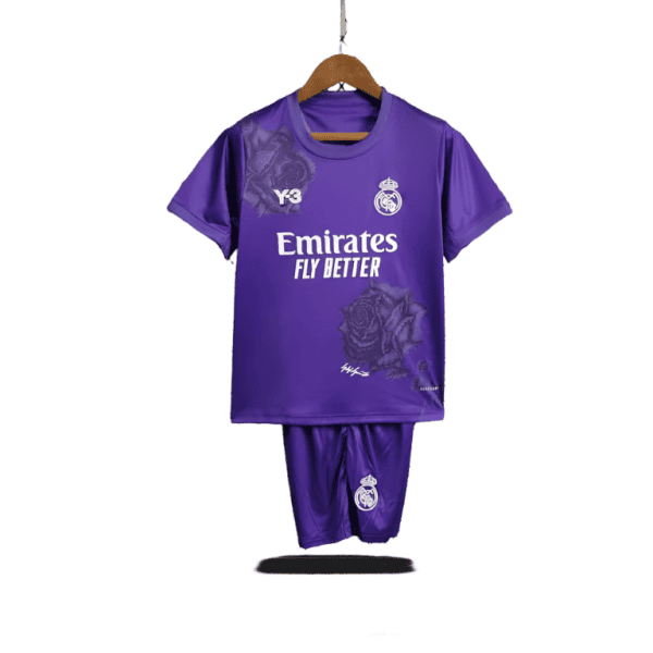 Purple Real Madrid football kit (jersey and shorts) hanging on a wooden hanger, featuring the Emirates Fly Better sponsor and club crest.