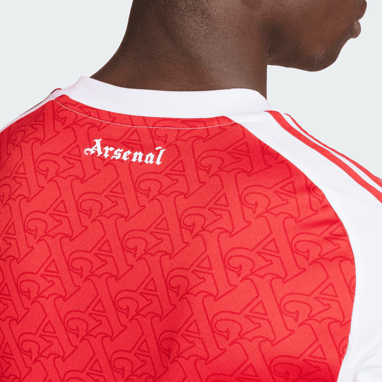 Screenshot2025-06-04185021 | AE JERSEY Back view of a person wearing a red Arsenal football jersey with a white collar and repeating pattern across the fabric, 'Arsenal' text near the neckline.