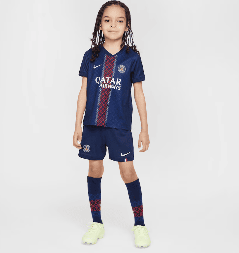 Screenshot_2025-06-23_232312 | AE JERSEY Young girl wearing a Paris Saint-Germain soccer kit in navy, with Qatar Airways sponsor, standing against a light background.