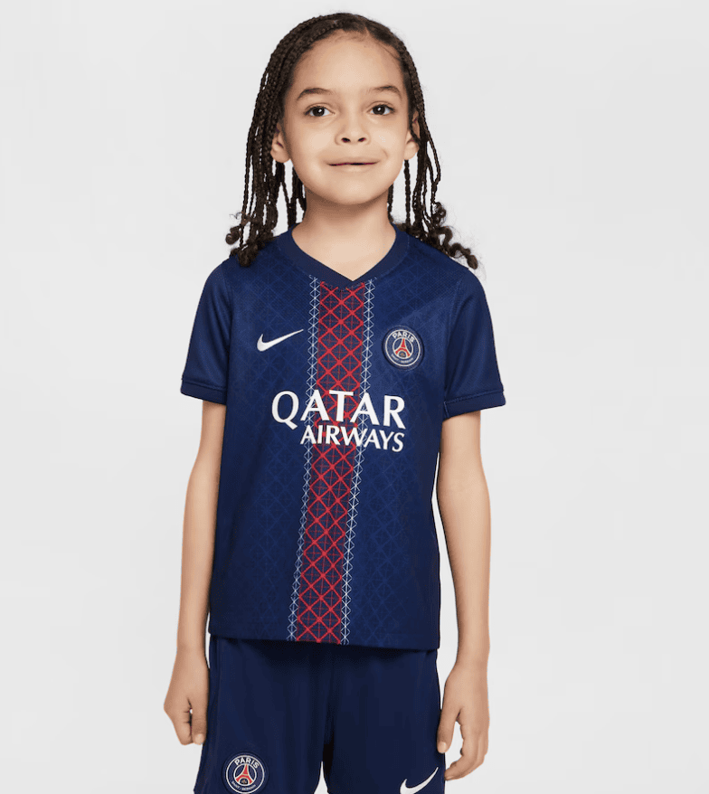 Screenshot_2025-06-23_232328 | AE JERSEY Young girl wearing a navy PSG soccer jersey with a red vertical stripe, sponsor logo, and club crest, standing against a light background.