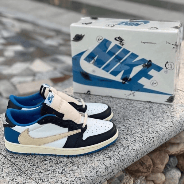 Pair of white, black, blue, and beige Nike sneakers resting on a stone ledge with a Nike shoebox in the background.