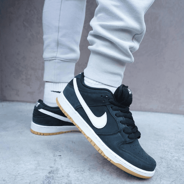 Close-up of navy Nike sneakers with white swoosh and gum-colored outsole, paired with gray joggers and white socks.