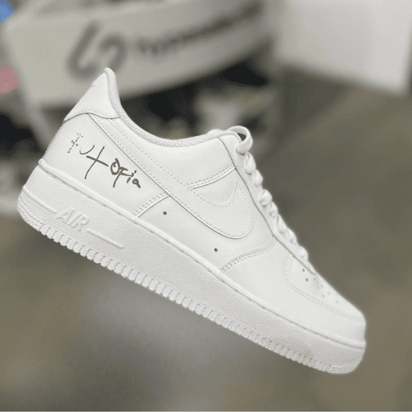 White low-top sneaker with a handwritten autograph on the heel area.