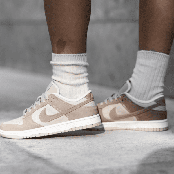 Person wearing beige Nike sneakers with white socks standing on a concrete surface.