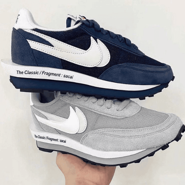 Stack of two Nike Sacai x Fragment sneakers, navy on top and gray underneath, with a white swoosh and midsole text visible.