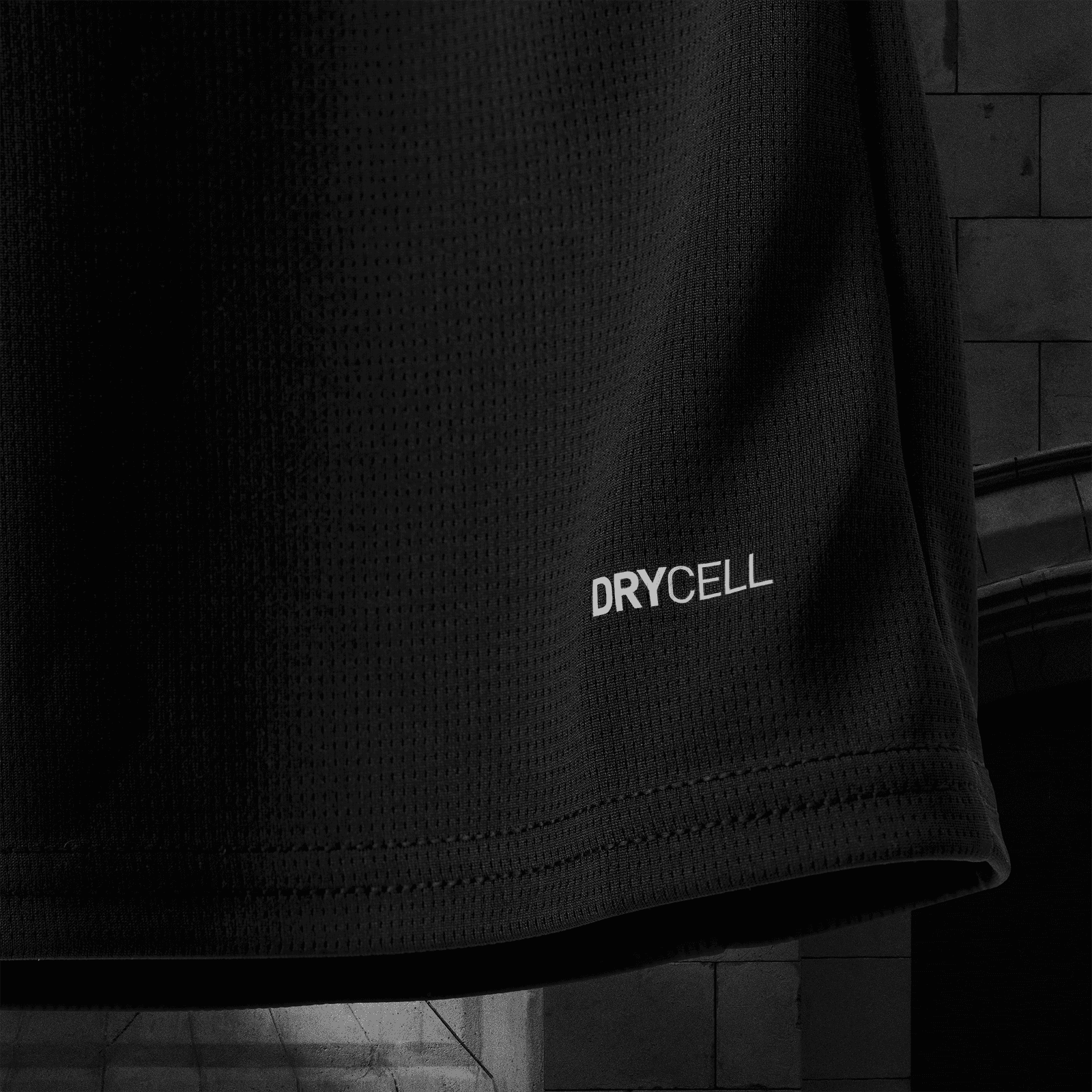 V4 | AE JERSEY Close-up of black perforated fabric with the word DRYCELL printed near the bottom edge.
