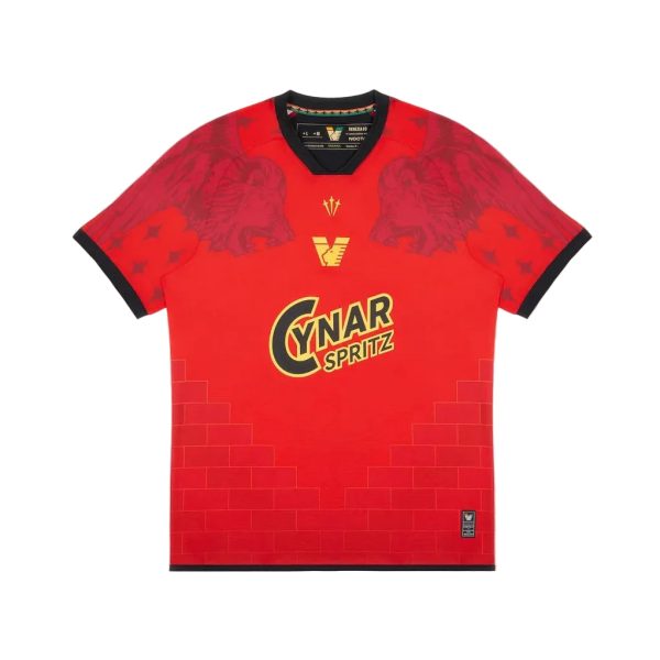 Red soccer jersey with black trim on the collar and cuffs, featuring the yellow Cynar Spritz logo on the chest and a subtle brick pattern at the lower front.