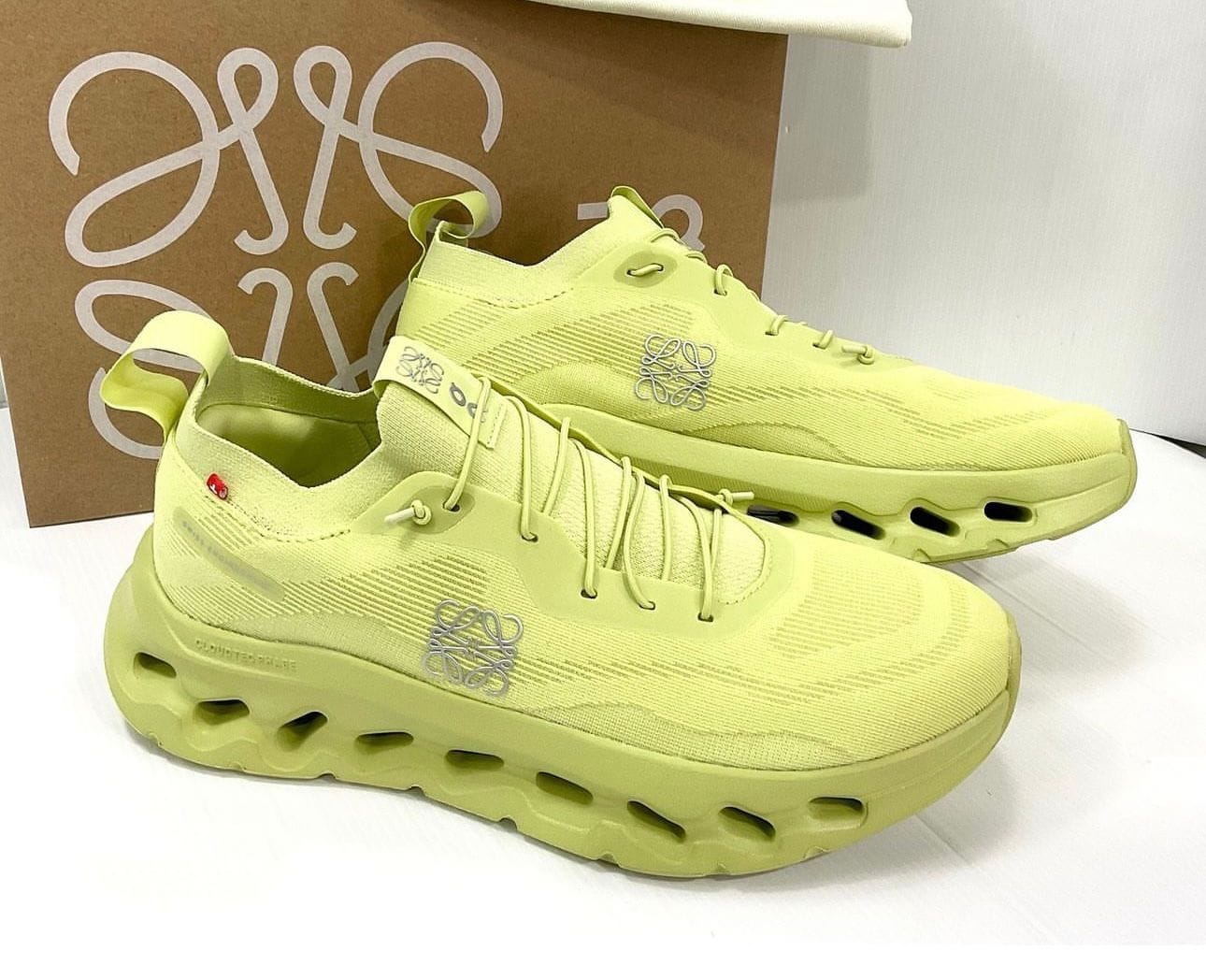 WhatsAppImage2024-07-22at18.36.48 | AE JERSEY Lime-yellow athletic sneakers with a chunky hollow-sole design, knits upper, and logo on the side, placed before a brown box.