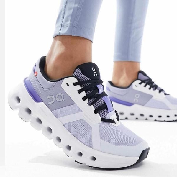 Light purple running shoes with black laces and a chunky white sole with circular cutouts, worn by a person in light leggings.] , but let's fix formatting.