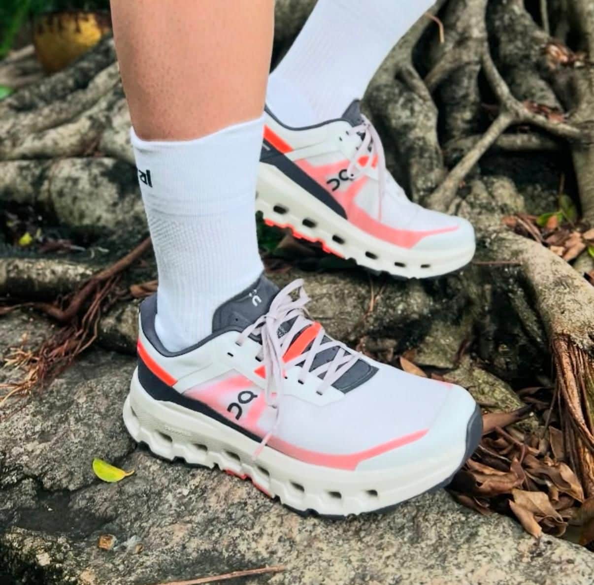 WhatsAppImage2025-02-21at13.47.19 | AE JERSEY White and pink On running shoes with thick soles, worn with white socks, stepping on rocky outdoor terrain.