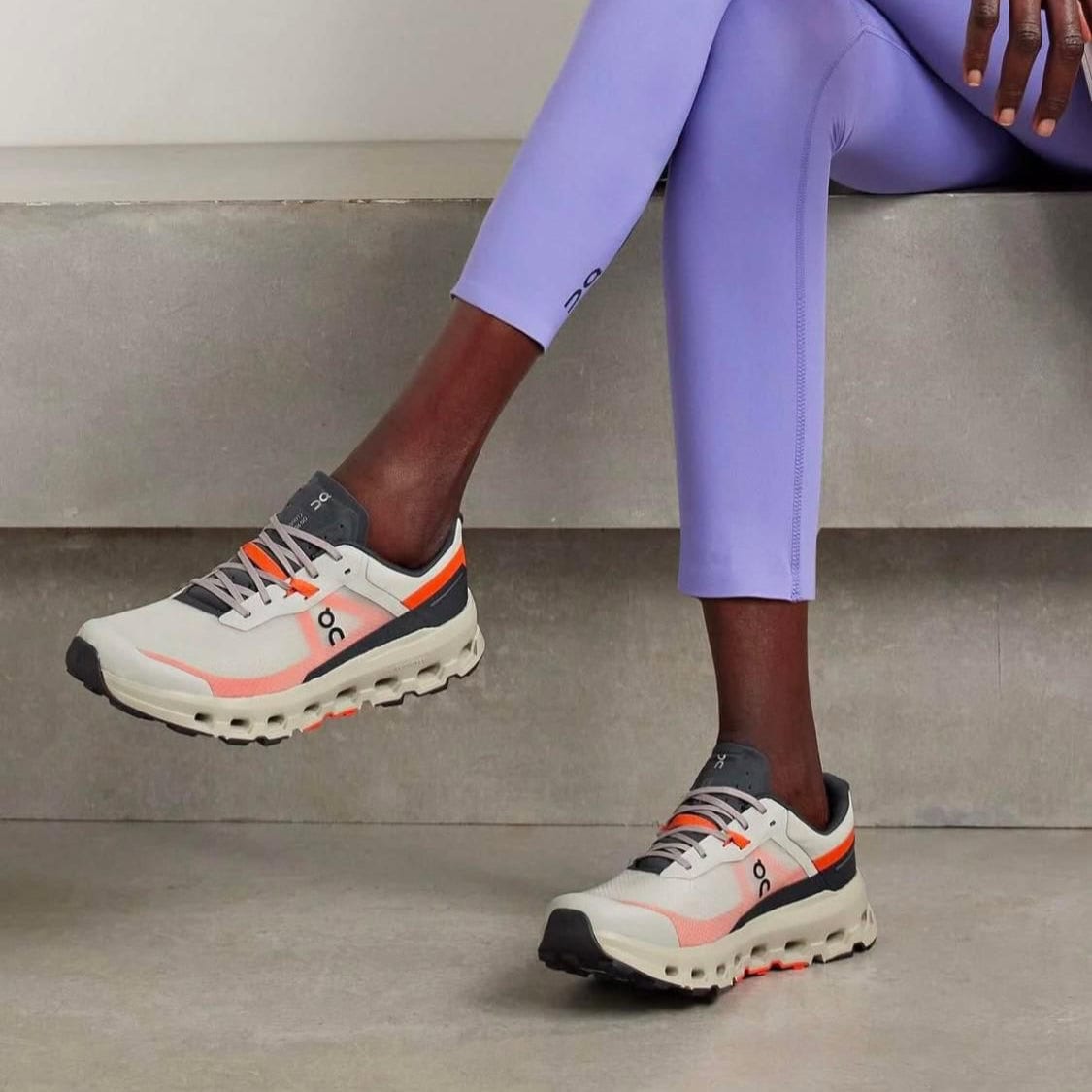 WhatsAppImage2025-02-21at13.47.34 | AE JERSEY Person wearing lavender leggings and chunky white sneakers with orange accents, stepping with one foot on a concrete step.